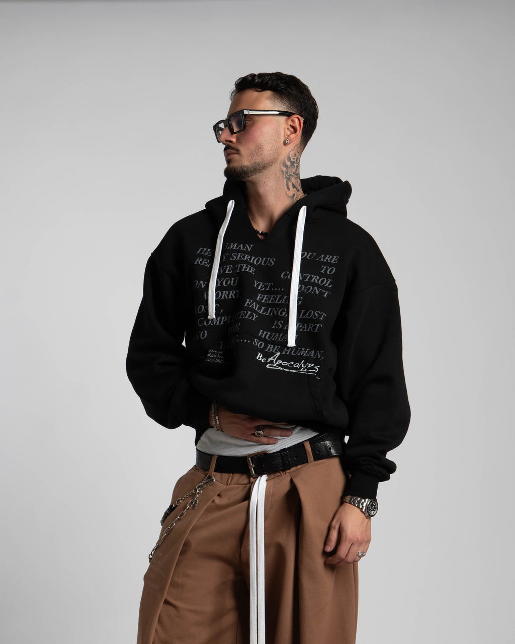 Man wearing a black hoodie and brown pants on a plain background