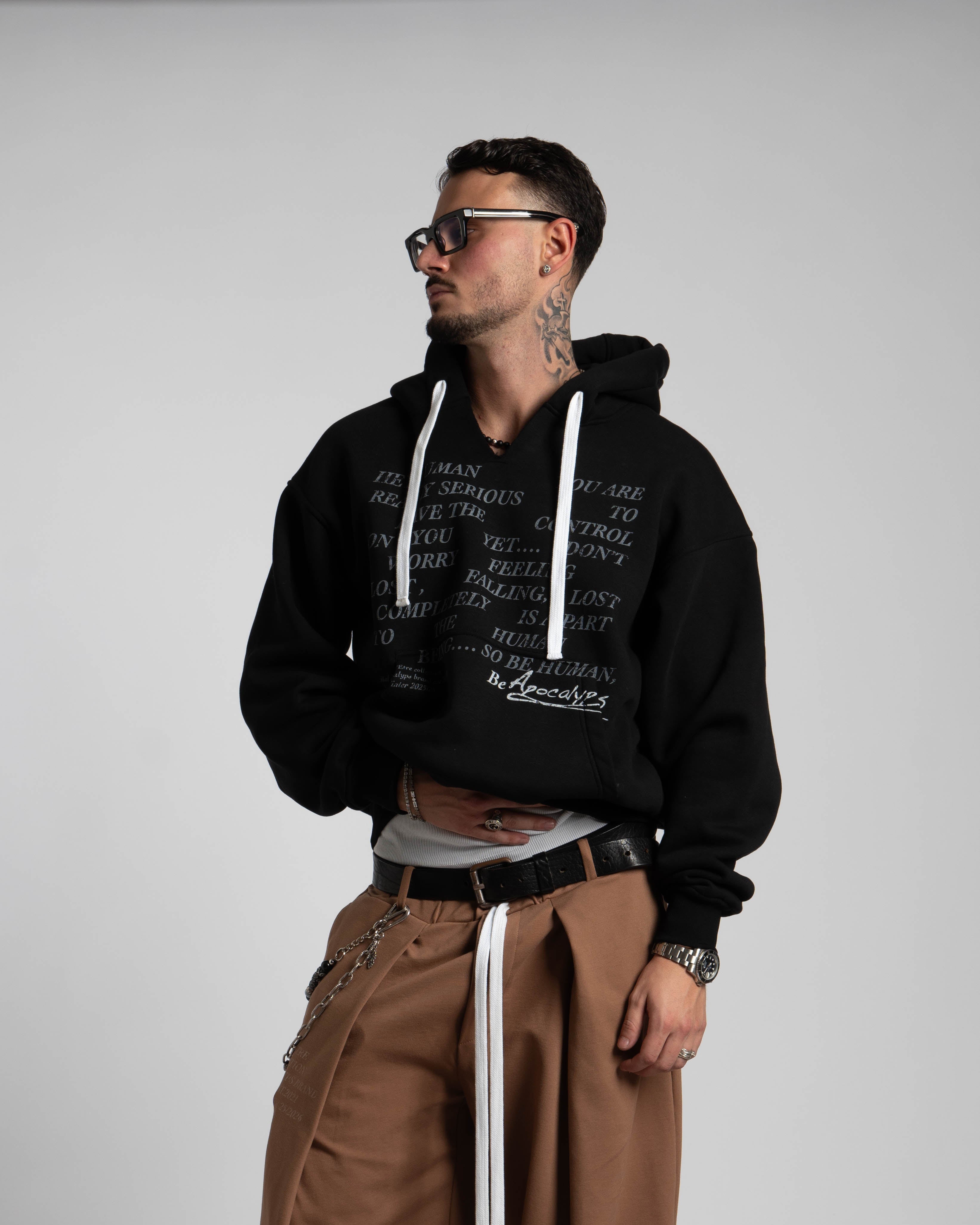 Man wearing a black hoodie and brown pants on a plain background